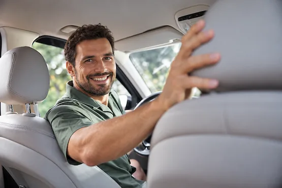 Chauffeur VTC souriant à bord d’une voiture, illustration des trajets dans l’Ain