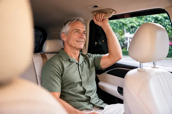 Homme souriant installé à l’arrière d’une voiture, illustration des trajets VTC dans l’Allier