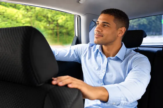 Homme installé à l’arrière d’une voiture, illustration des trajets VTC en Ardèche