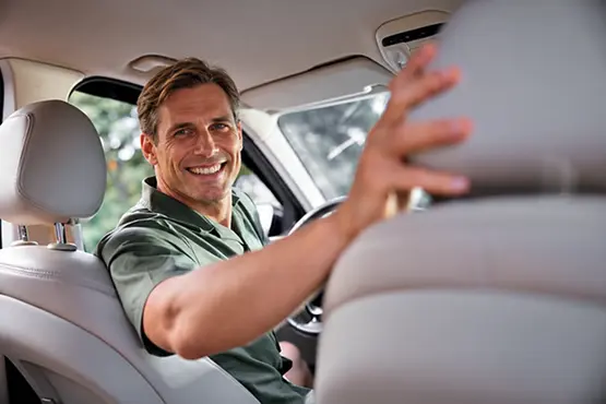 Chauffeur souriant à bord d’une voiture, illustration des trajets VTC dans le Cantal