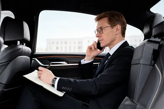 Passager en costume au téléphone prenant des notes dans une voiture — illustration VTC : Creuse