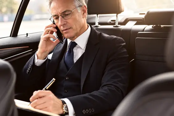 Passager en costume au téléphone prenant des notes dans une voiture, illustration VTC dans le Doubs