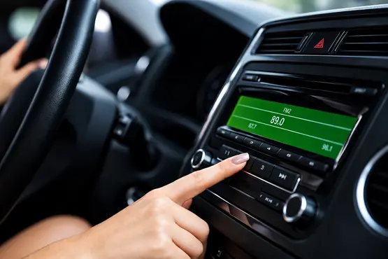 Main réglant l’autoradio d’une voiture, illustration VTC dans l’Indre