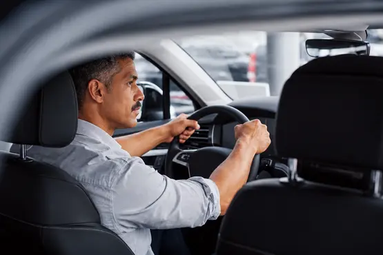 Conducteur au volant vu depuis l’arrière d’une voiture, illustration VTC dans le Jura