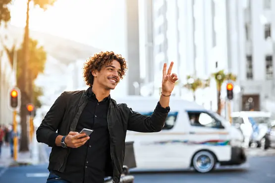 Voyageur avec un téléphone levant la main dans une rue, illustration VTC en Haute-Loire