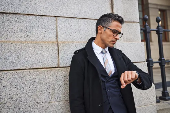 Homme en costume consultant sa montre dans une rue — illustration VTC : Lot-et-Garonne