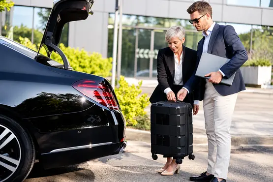 Deux personnes déposant une valise près du coffre d’une berline, illustration VTC en Meurthe-et-Moselle