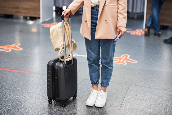 Voyageuse avec une valise et un sac dans un terminal — illustration VTC : Sarthe
