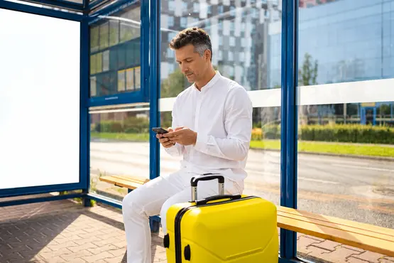 Voyageur avec une valise jaune consultant son téléphone dans un abri, illustration VTC en Seine-et-Marne