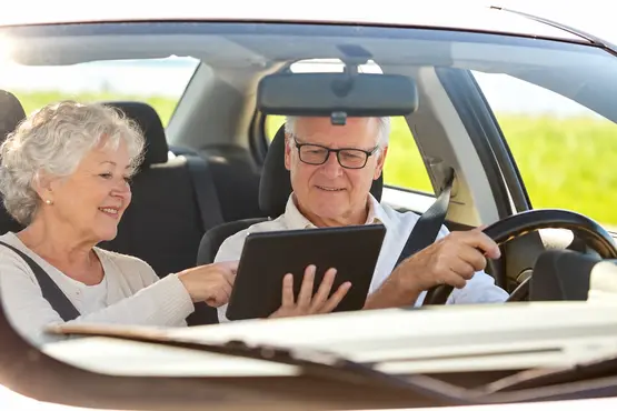 Couple senior consultant une tablette dans une voiture à l’arrêt, illustration VTC dans les Yvelines